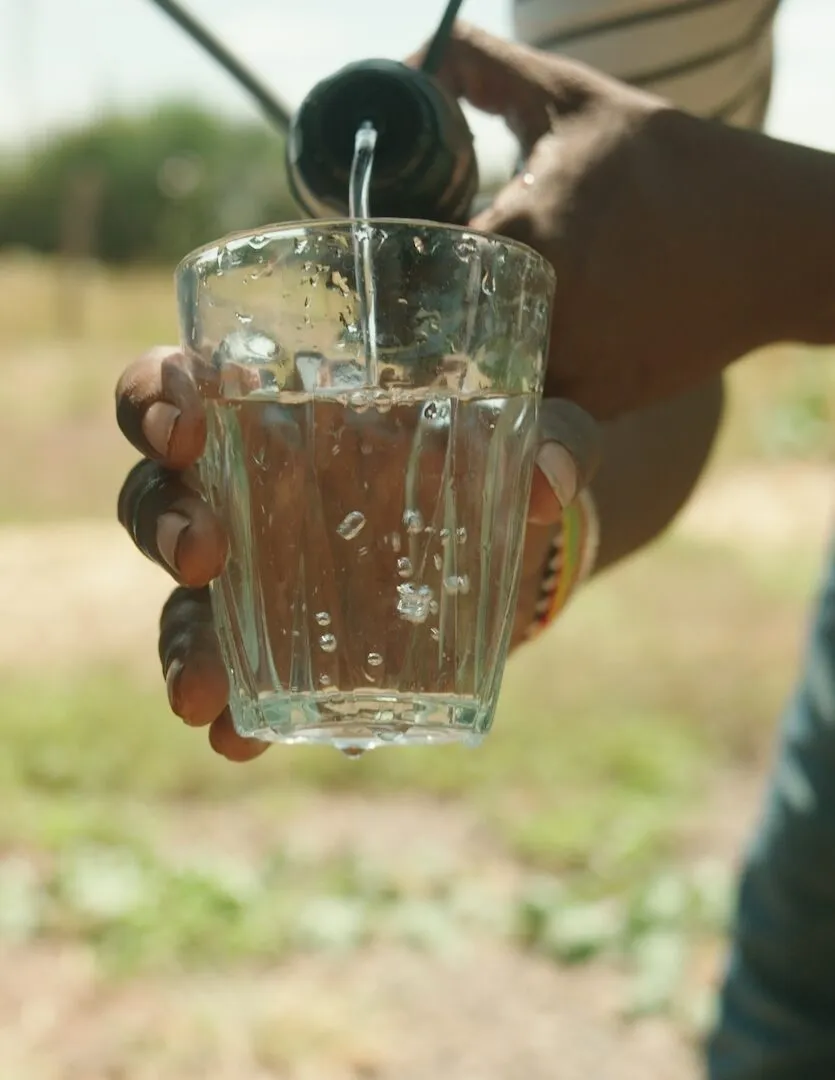 A person filtering dirty water into a glass using a water filter